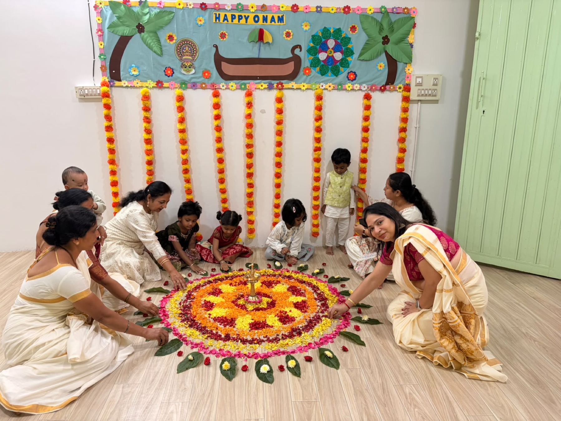 Children, families and teachers arranging an Onam flower rangoli at Tender Moments Hebbal