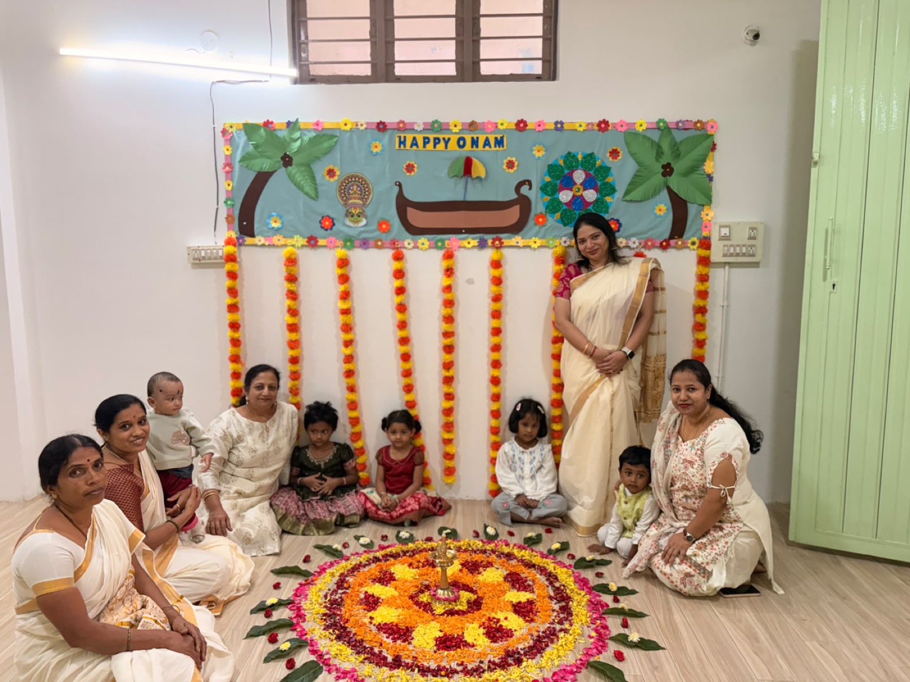 Children and teachers gathered around an Onam flower rangoli at Tender Moments Hebbal