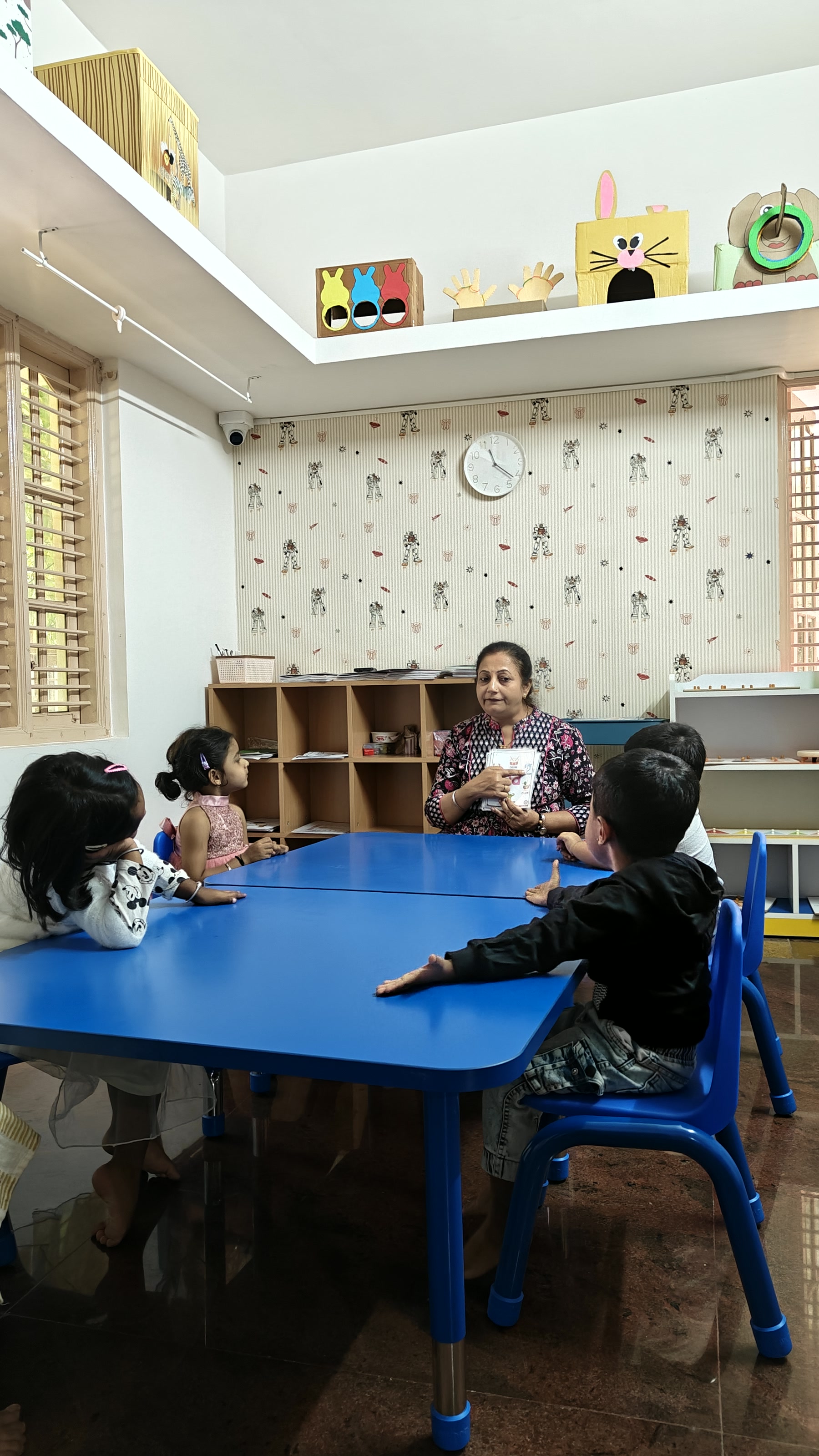 Children gathered around a blue table with a guide at Tender Moments Hebbal