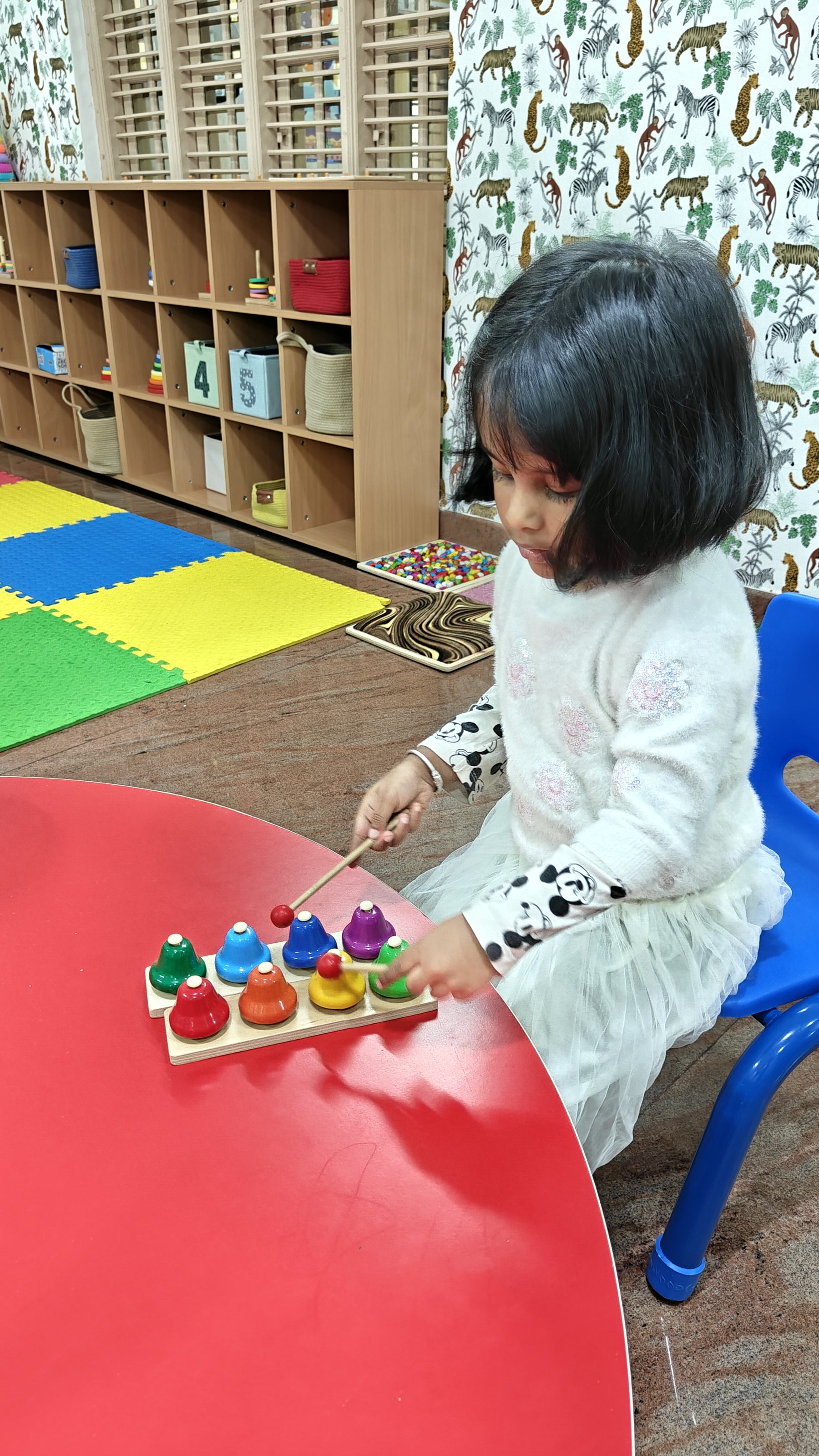 Child engaged in hands-on learning at a red table